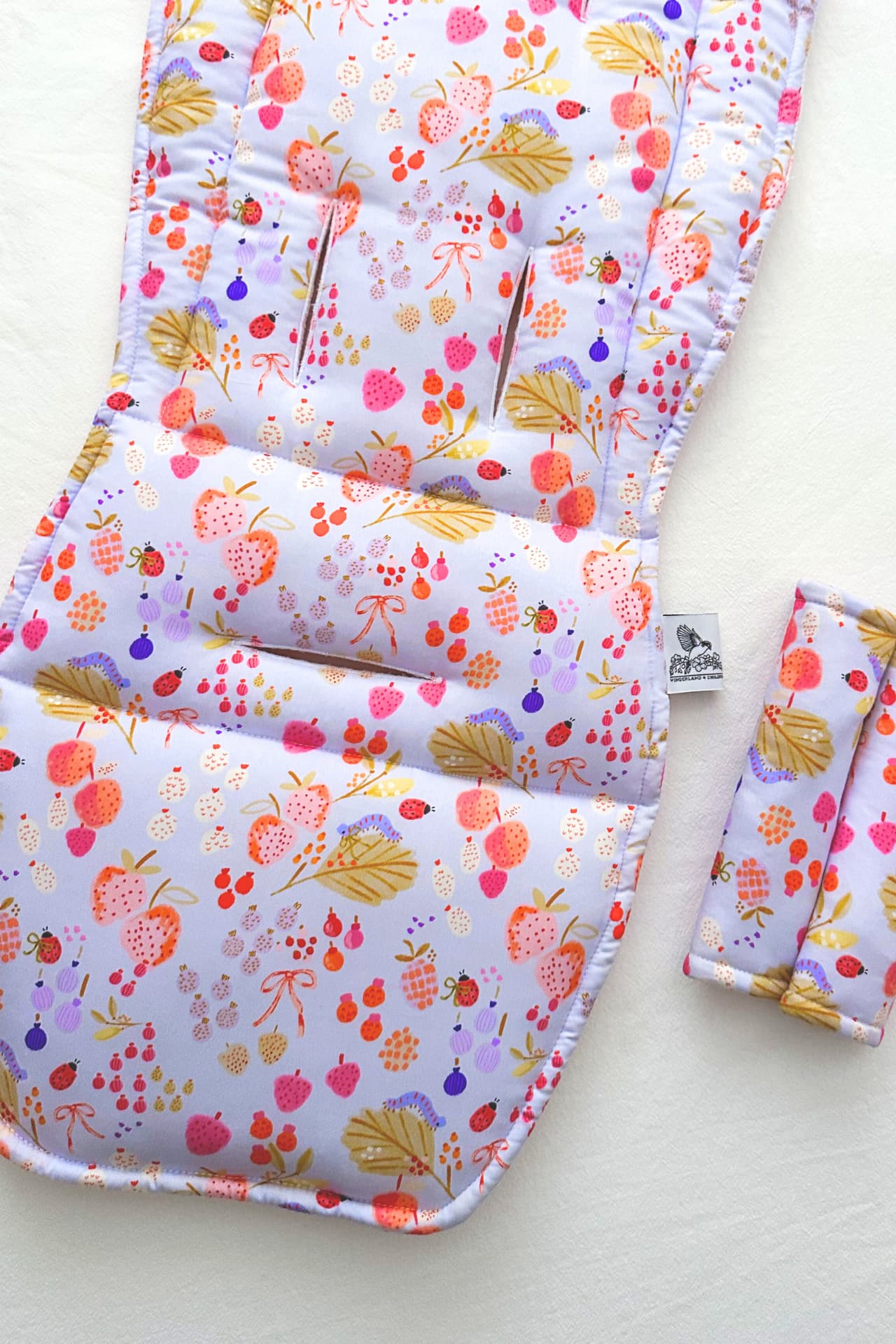 Floral-patterned baby seat cover with matching pouch on a light background