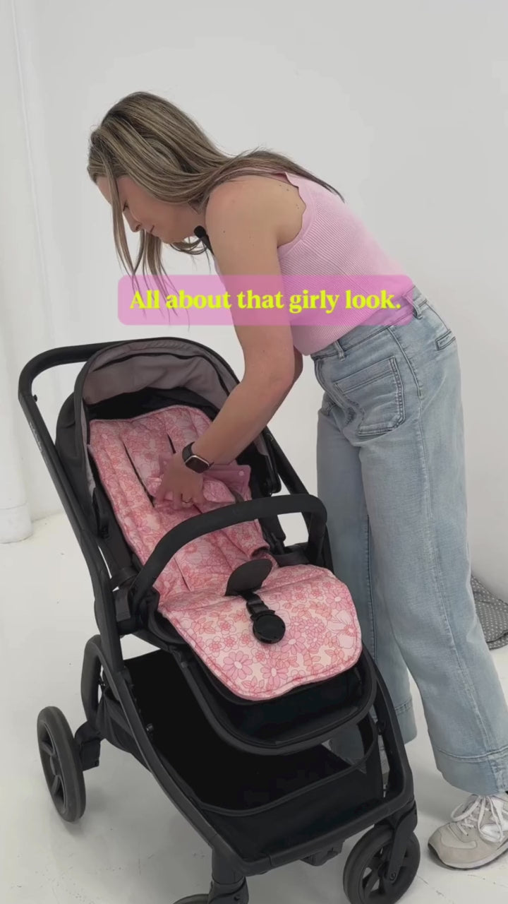 Woman installing pink floral universal pram liner in black stroller for baby comfort, style, and easy cleaning.