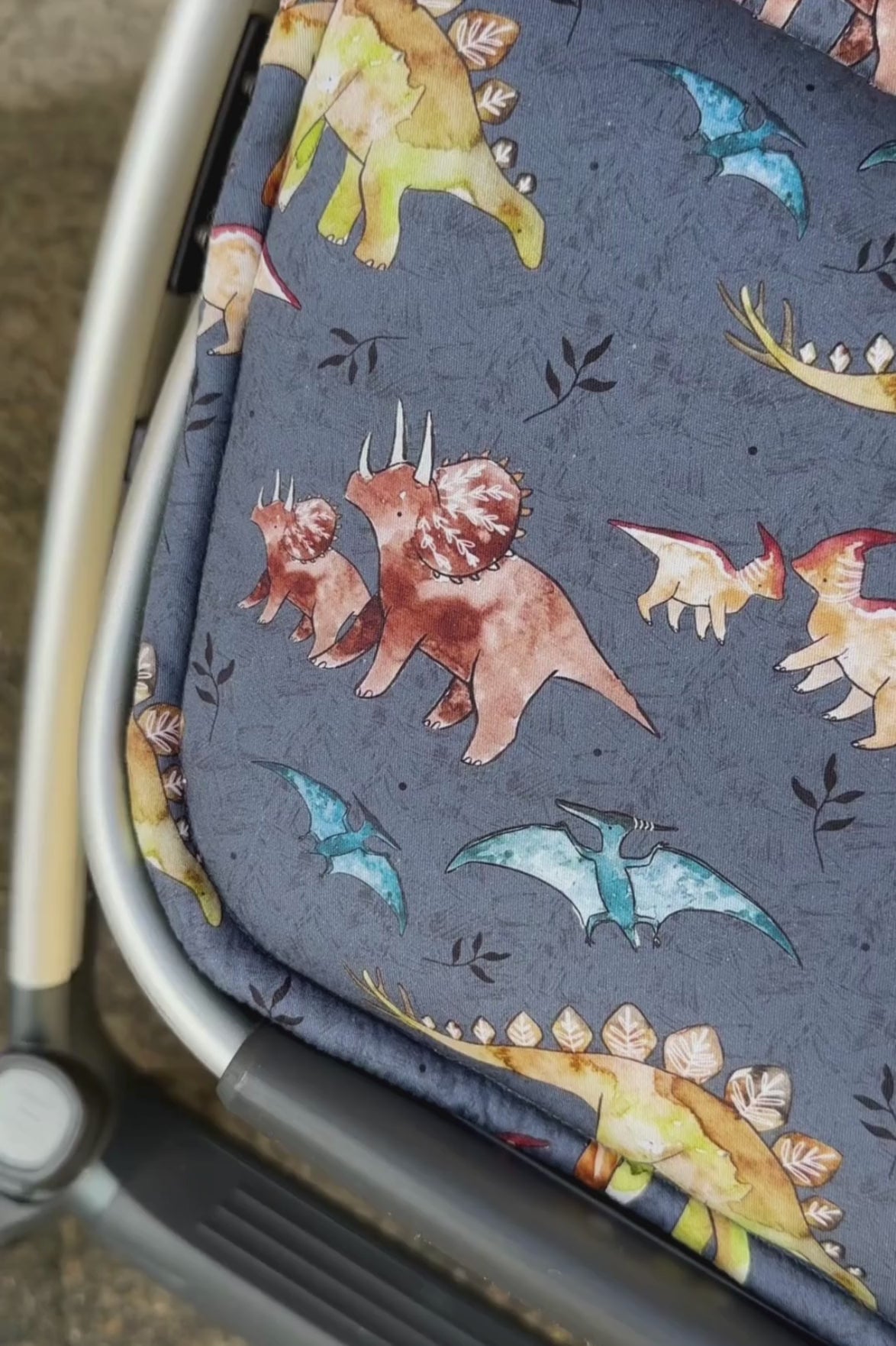 Close-up of blue dinosaur print universal pram liner for stroller, showing fit, OEKO-TEX cotton, and reversible quality.
