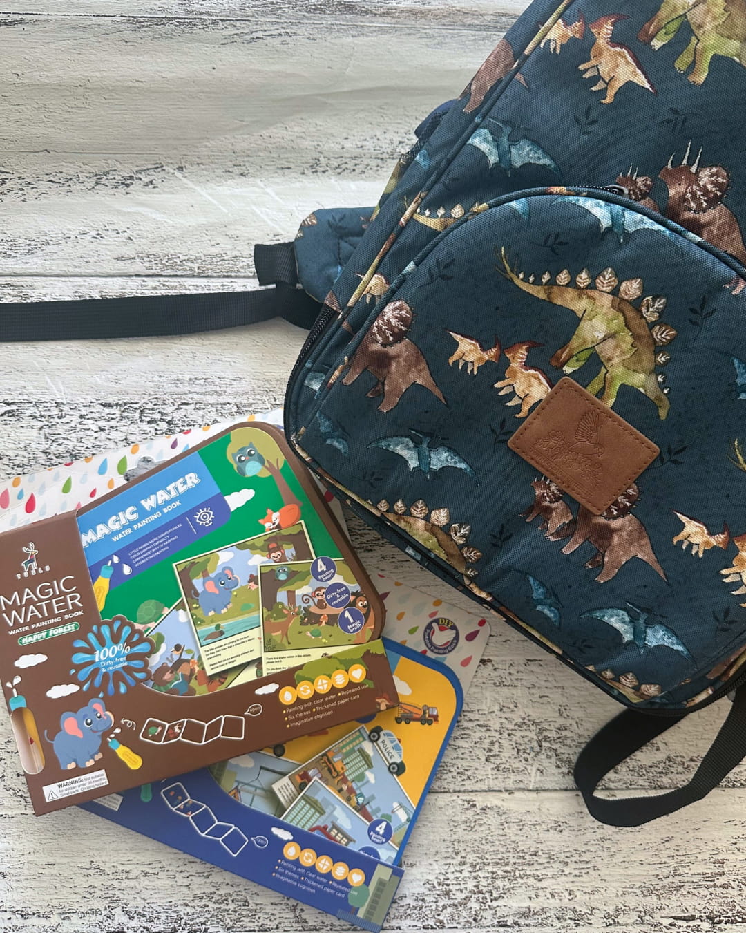 Dinosaur-patterned bag with educational books on a wooden surface