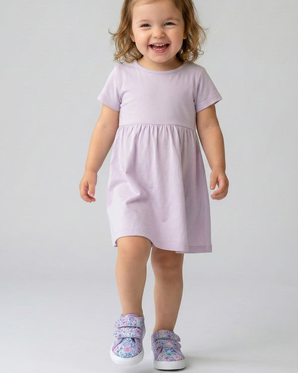 Child wearing a light purple dress on a plain background
